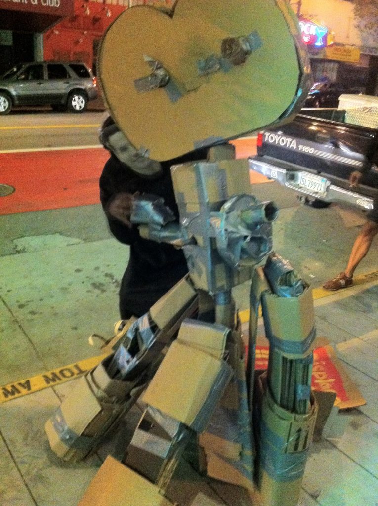 ghost movie director gavin newsom poses behind a cardboard movie camera on a tripod