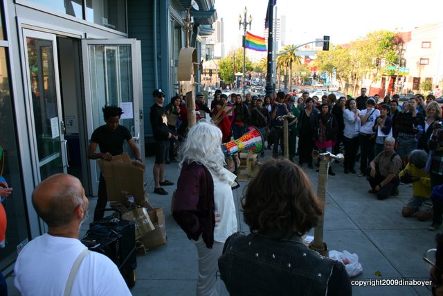 A crowd of people including someone with silvery hair on a bullhorn and 50 or more people who are ready for action.