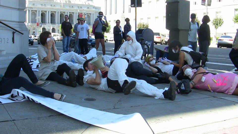 a group of people staging a die-in at the front steps of the department of public health