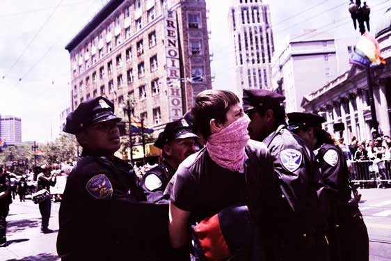 medium shot of police cuffing and strong-arming person in pink bandana in the market street pride parade route