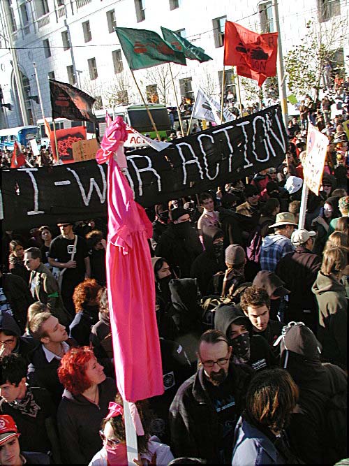 overhead shot of tons of people marching in front of the black "anti-war action" banner