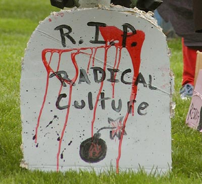 fake blood stains a cardboard tombstone reading: "r.i.p. radical culture"