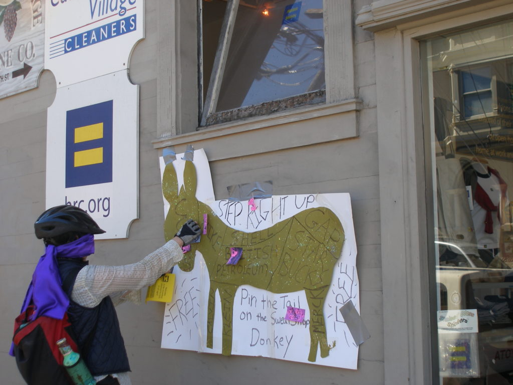 person playing pin the tail on the sweatshop donkey on the side of the hrc.org store exterior at castro on 19th