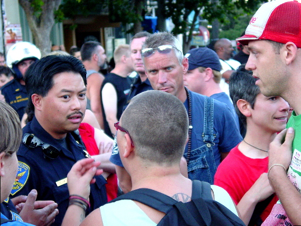 medium shot of people in a crowd confronting a police office with an apparently confused expression
