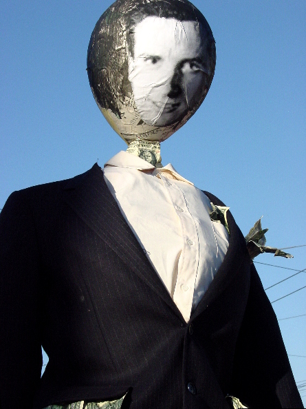 close-up of a gavin newsom effigy with a b/w photocopied image of his face plastered on a balloon in a pinstriped suit stuffed with money