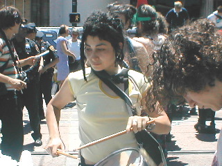 person with a drum standing in a crowd at market and 8th at the end of the parade route