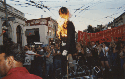 shot of the gavin newsom effigy going up in flames in front of a cheering crowd blocking the street at castro and 18th