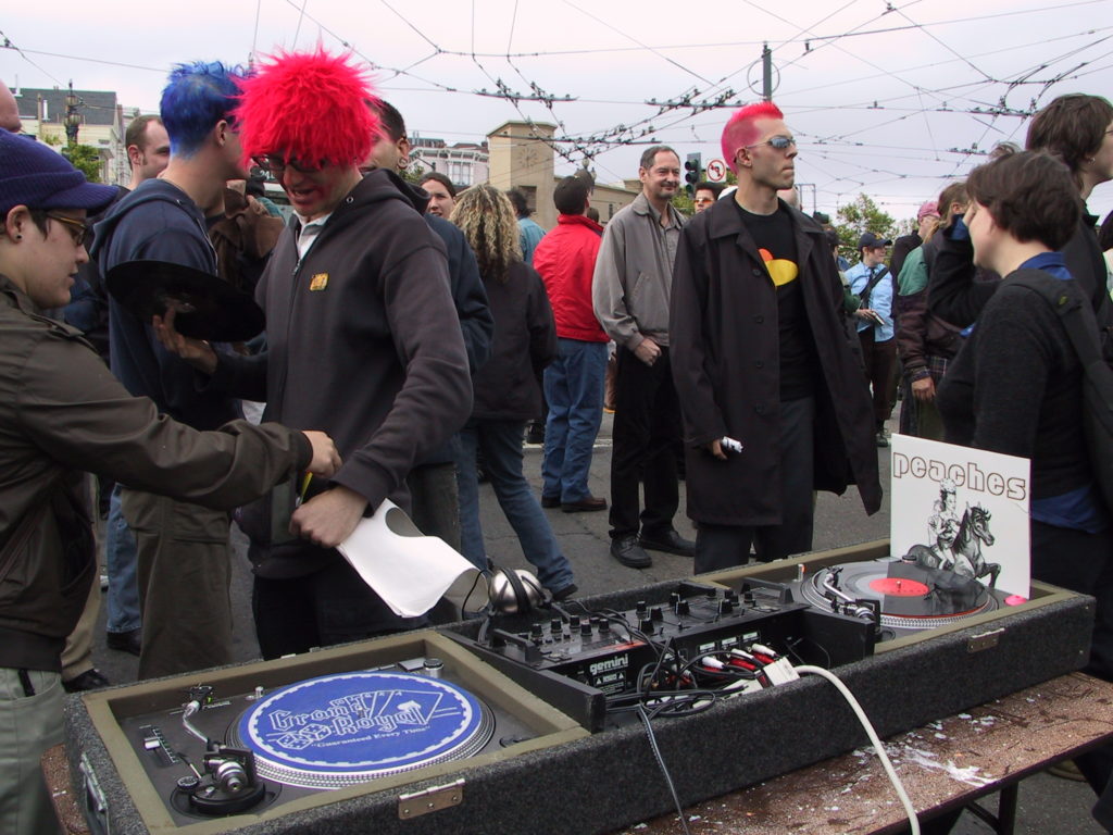 a disc jockey has set up turntables at harvey milk plaza as a crowd lingers after the award ceremony