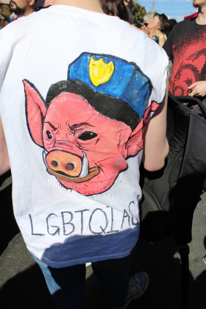 person wearing a tshirt with a pig head wearing a police cap "lgbtqiacab"