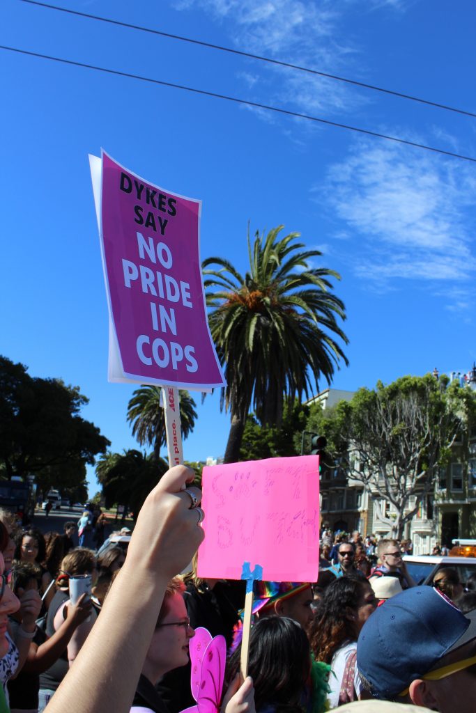 "dykes say no pride in cops" sign in the foreground  as people fill the intersection