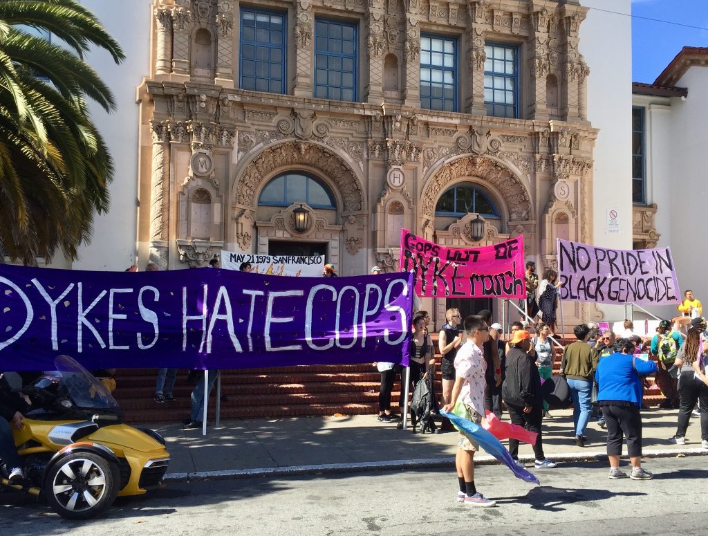 people gathering on the steps of mission high with banners reading "dykes hate cops" "cops out of dyke march" and "no pride in black genocide"